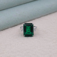 Ring with a green gemstone on a light gray background, Emerald Cut CZ Trilogy Ring, Green and White CZ Three Stone Ring
