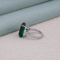 Silver ring with a green gemstone on a neutral background, green CZ engagement ring, emerald cut center stone, white CZ side stones, symbolic trilogy ring, past present future ring, green emerald ring, affordable gemstone ring, CZ engagement jewelry, emerald cut trilogy ring