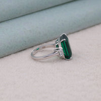 Silver ring with a green gemstone on a light gray surface, Modern CZ Trilogy Ring, Green CZ Cocktail Ring