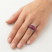Hand wearing a ring with red gemstones on a white background