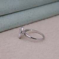 Silver ring with a heart-shaped diamond on a beige surface, Bezel Set Split Shank Oval Solitaire Engagement Ring, Oval Cut Wedding Ring For Women, Modern Bezel Set Bridal Jewelry