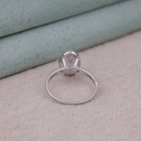 Silver ring with a diamond on a textured surface, Sustainable Oval Moissanite Engagement Ring, Conflict Free Oval Solitaire Wedding Band, Elegant Split Shank Bridal Engagement Ring