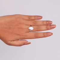Hand wearing a silver ring with a clear gemstone on a light gray background, Oval Bezel Set Split Shank Engagement Ring, Elegant Solitaire Wedding Jewelry