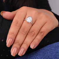 Close-up of a hand wearing a diamond ring with a blurred background, Bezel Set Oval Engagement Ring, Split Shank Solitaire Wedding Jewelry