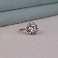 Silver ring with a large central gemstone and smaller stones on a light gray surface