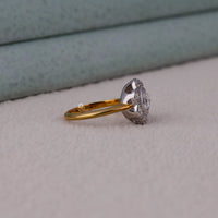 Gold and silver ring with a diamond on a light gray surface