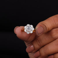 Gold ring with a diamond held between fingers against a black background