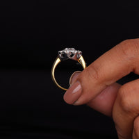 Gold ring with a diamond held between fingers against a black background