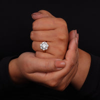Close-up of a hand wearing a diamond ring against a black background