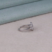 Silver ring with a diamond on a light gray surface, romantic Moissanite ring, antique-inspired Moissanite ring, floral design engagement ring, Moissanite heirloom ring, Moissanite wedding band, nature-inspired engagement ring, eco-friendly bridal rin