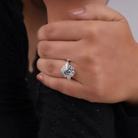 Close-up of a hand wearing a silver ring with a dark gemstone against a blurred background, Moissanite Petal Halo Ring, Vintage Style Moissanite Ring