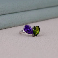 Ring with purple and green gemstones on a neutral background