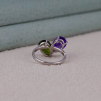 Silver ring with purple gemstone on a light gray surface