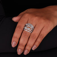 Hand wearing multiple diamond rings on a black background