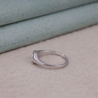 Silver ring on a textured surface with a neutral background, Elegant Flush Setting Oval Engagement Ring, Durable 14K Gold Moissanite Bridal Ring, Unique Modern Oval Engagement Ring