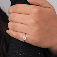 Close-up of a hand wearing a diamond ring on a plain background, Conflict Free Heart Cut Bridal Ring, Sustainable Moissanite Engagement Ring, Timeless Solitaire Heart Moissanite Ring