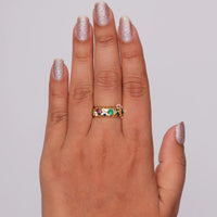 Hand wearing a gold ring with colored gemstones against a gray background, Round Cut Colorful CZ Celestial Band – Star Shape Flush Setting Stacking Ring