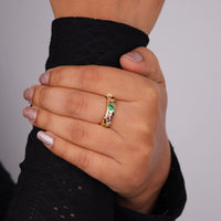 Hand wearing a gold ring with colored gemstones against a gray background, Celestial Star Design Band – Round Colorful CZ Gemstones Flush Set Ring