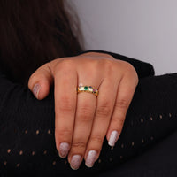 Hand wearing a gold ring with a green gemstone on a dark background, Colorful CZ Star Shape Celestial Band – Round Gemstone Flush Setting Ring