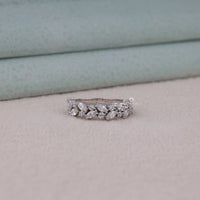 Silver ring with marquise-shaped diamonds on a soft fabric background