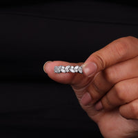 Hand holding a diamond ring against a black background