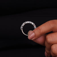 Hand holding a diamond ring against a black background