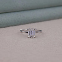 Diamond ring with emerald-cut gemstone on a neutral background