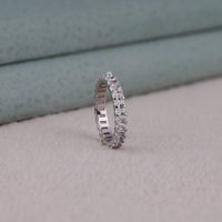 Silver ring with diamonds on a light gray surface