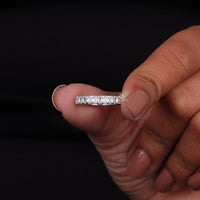 Hand holding a diamond ring against a black background