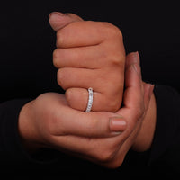 Hand wearing a diamond ring against a black background