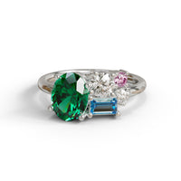 Elegant ring with green, blue, and pink gemstones on a white background, green oval CZ ring, aquamarine baguette CZ ring, pink and white CZ ring, five stone CZ ring, multi-color CZ engagement ring, colorful CZ bridal ring, gemstone inspired ring, engagement ring alternative, vibrant CZ ring, oval cut green CZ ring