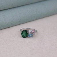 Silver ring with green, blue, and pink gemstones on a light gray surface,  fine CZ jewelry, dainty five stone ring, radiant cut CZ ring, synthetic gemstone ring, stacking CZ ring, gemstone inspired proposal ring