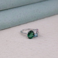 Silver ring with a green gemstone on a light gray surface, Green Oval CZ Ring, Aquamarine Baguette Ring, Pink and White CZ Ring, Colorful CZ Engagement Ring