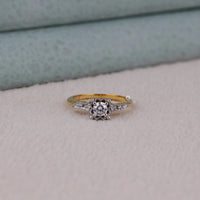 Gold and silver ring with a diamond on a light gray surface