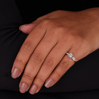 Hand wearing a diamond ring on a black background