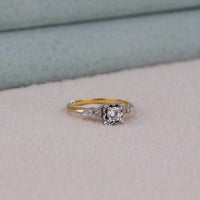 Gold and silver ring with a diamond on a light gray surface