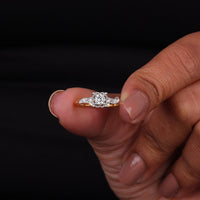 Gold ring with a diamond held between fingers against a black background