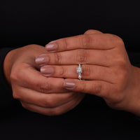 Close-up of a hand wearing a diamond ring on a black background