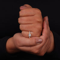 Hand holding a diamond ring against a black background