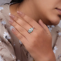 Close-up of a hand wearing a diamond ring with a blurred floral-patterned garment in the background, Edwardian filigree ring, Art Deco filigree shank, engraved antique ring, vintage bridal ring, engraved engagement band, retro inspired ring, filigree engagement ring, 1920 engraving style ring, romantic vintage ring, intricate antique style ring
