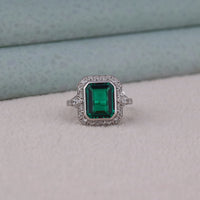 Ring with a green gemstone and diamond accents on a neutral background