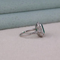 Silver ring with a green gemstone on a light gray surface
