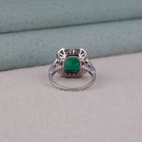 Silver ring with a green gemstone on a textured surface