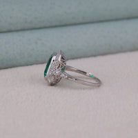 Silver ring with a green gemstone on a light gray surface