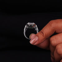 Silver ring with a large diamond held by a hand against a black background
