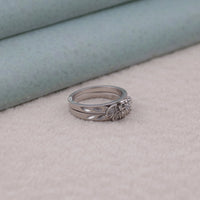 Two silver rings stacked on a light pink surface with a light blue background, vintage moissanite band, affordable bridal set moissanite, handcrafted moissanite ring, filigree moissanite bridal set