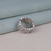 Silver ring with gemstones on a light gray surface, Modern Bezel Set Moissanite Eternity Ring, Sustainable Moissanite Stackable Band, Elegant Round Moissanite Anniversary Ring