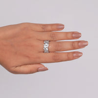 Hand wearing a silver ring with small stones on a light gray background, Sparkling Bezel Round Moissanite Promise Ring, Minimalist Moissanite Stackable Jewelry Band