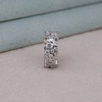 Silver ring with embedded diamonds on a light gray surface, Bubble Bezel Set Round Moissanite Eternity Wedding Band, Stackable Anniversary Ring For Women, Round Cut Moissanite Wedding Ring, Bubble Style Moissanite Bridal Jewelry