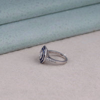 Silver ring with blue gemstone and clear stones on a light gray surface, unique halo ring, handmade CZ ring, heirloom style jewelry, sapphire promise ring, affordable sapphire CZ ring, elegant sapphire cocktail ring